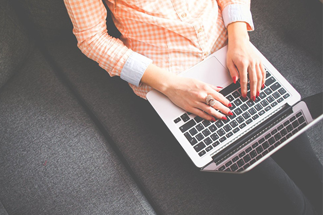 person sitting on couch working on laptop